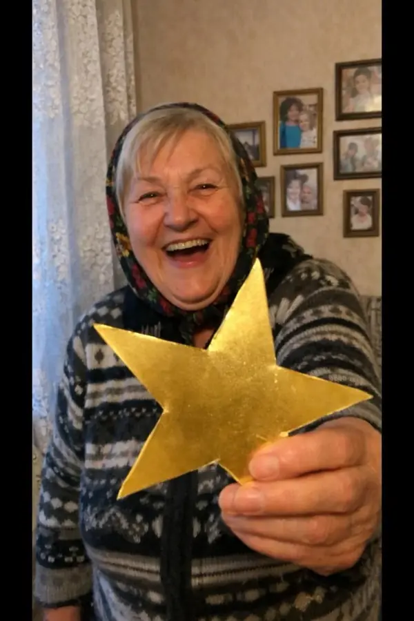 A grandmother laughing and holding up a paper star
